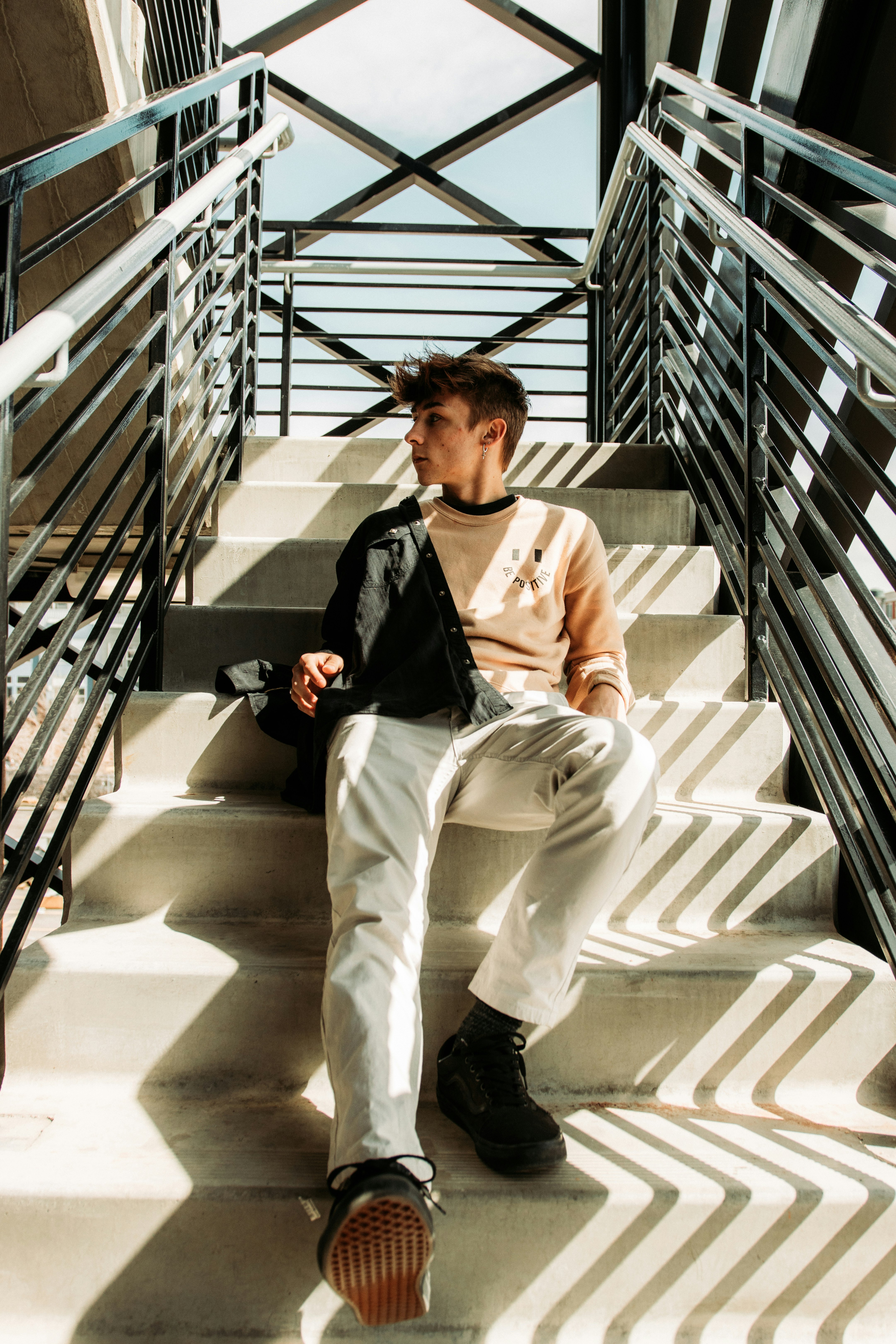 man in white pants sitting on white staircase